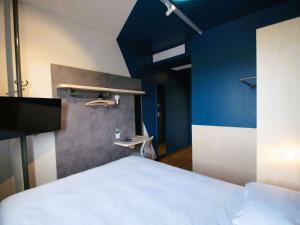 a bedroom with a white bed and a blue wall at ibis budget Loudéac Vélodrome in Loudéac