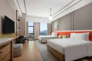 a hotel room with two beds and a desk at Hilton Garden Inn Shenzhen Guangming Hongqiao Park in Shenzhen