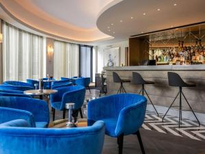 um restaurante com cadeiras azuis e um bar em Le Louise Hotel Brussels - MGallery em Bruxelas
