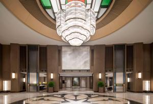 een lobby met een grote kroonluchter en een gebouw bij Yuexiu Hotel Guangzhou Curio Collection By Hilton, Free Shuttle during Canton Fair in Guangzhou
