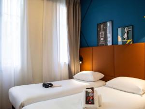 dwa łóżka siedzące obok siebie w pokoju w obiekcie ibis Paris Ornano Montmartre Nord 18ème w Paryżu