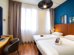 a hotel room with two beds and a desk at ibis Paris Ornano Montmartre Nord 18ème in Paris