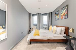 um quarto com uma cama grande com almofadas brancas e amarelas em ShyRoyale em Londres