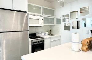 a kitchen with white cabinets and a stainless steel refrigerator at 2 BEDROOM ON THE BEACH ! in Miami Beach