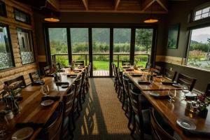 a dining room with long tables and chairs and windows at Seward Windsong Lodge in Seward