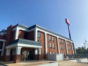 a brick building with a flag on top of it at HomeTowne Studios by Red Roof Prattville in Prattville