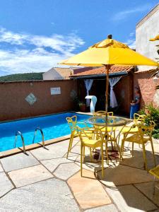 um guarda-sol amarelo e cadeiras ao lado de uma piscina em Vila Vitória Pousada em Pirenópolis