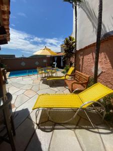 a patio with yellow chairs and a swimming pool at Vila Vitória Pousada in Pirenópolis
