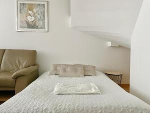 a bed in a room with a chair and a picture at 90 m2 Maisonette with Free Parking in Vienna