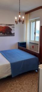 a bedroom with a blue bed with a chandelier at house Al Cascinale in San Severino Marche