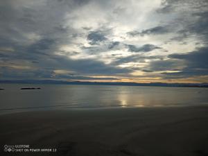 a cloudy sky over the water on a beach at Clarks beach batch snatch in Auckland