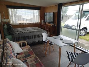 a room with a bed and a couch and a table at Clarks beach batch snatch in Auckland