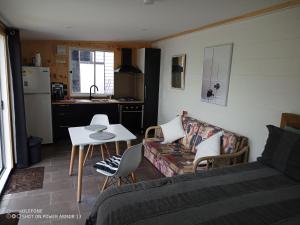 a living room with a couch and a table and a kitchen at Clarks beach batch snatch in Auckland
