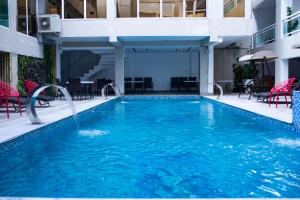 ein Schwimmbad in einem Hotel mit roten Stühlen und Tischen in der Unterkunft SANA Hotel in Abidjan