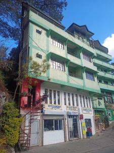 ein grünes und weißes Gebäude auf einer Straße in der Unterkunft Pas-it Hostel Sagada in Sagada