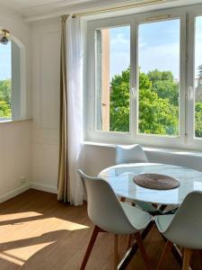 ein Esszimmer mit einem Tisch, Stühlen und Fenstern in der Unterkunft 2 bedrooms, 15min from Paris, free parking in Deuil-la-Barre