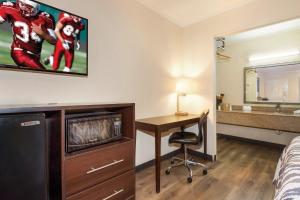 a hotel room with a desk and a football picture on the wall at Red Roof Inn Santee in Santee