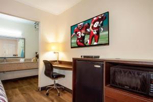 a hotel room with a desk and a tv on the wall at Red Roof Inn Santee in Santee
