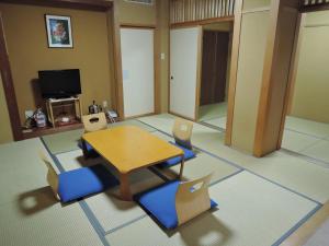 a living room with a wooden table and chairs at Maruni Ryokan in Hakuba