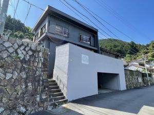 uma casa com uma parede de pedra e uma garagem branca em IHOKI BASE - Vacation STAY 57543v em Kumano