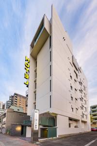 a tall white building with a yellow sign on it at Hotel Oak Shizuoka in Shizuoka