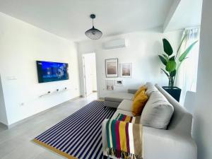 een witte woonkamer met een bank en een tapijt bij Arenales del sol, primera linea de playa in Arenales del Sol