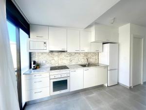 uma cozinha com armários brancos e um frigorífico em Arenales del sol, primera linea de playa em Arenales del Sol