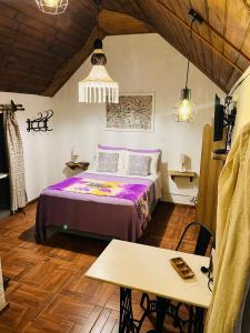1 dormitorio con cama morada y mesa en Altillo Valizas, en Barra de Valizas