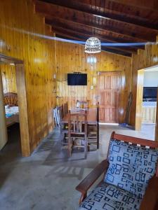 a dining room with wooden walls and a table and chairs at Cabaña Buena Madera in San Vicente
