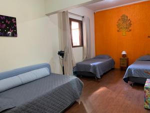 a room with two beds and an orange wall at Chácara Refrigério in Salto