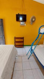 a room with a tv on a yellow wall at Cool & Calm Hotel in Manzanillo
