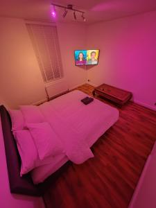 a pink bedroom with a bed and a flat screen tv at Magnolia Palazzo in London
