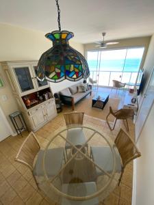 a living room with a glass table and a chandelier at Guarujá Pé na Areia in Guarujá