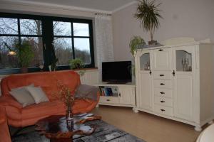 ein Wohnzimmer mit einem Sofa, einem TV und einem Schrank in der Unterkunft Apartment in Sehlen/Insel Rügen 3075 in Sehlen