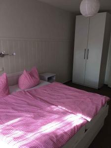 Schlafzimmer mit einem Bett mit rosa Bettwäsche und einem weißen Schrank in der Unterkunft Holiday home in Bergen/Insel Rügen 2847 in Bergen auf Rügen