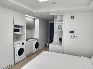 Sokcho Summitbay 1701 "Ocean View" في سوكشو: غرفة نوم بيضاء فيها سرير وغسالة ملابس