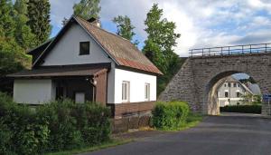 Holiday home Nove Hamry/Erzgebirge 1646 في Nové Hamry: بيت ابيض صغير بسقف احمر بجانب قوس