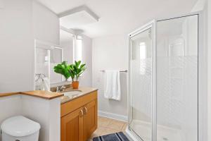 a white bathroom with a shower and a sink at The Lakeshore Cozy Cottage! in Wonder Lake