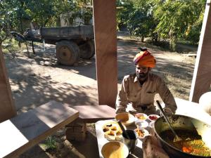 a man sitting at a table with a pot of food at Anokho in Nīmāj