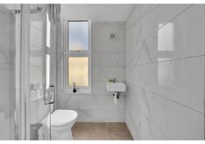 een witte badkamer met een toilet en een wastafel bij The Chill Spot: Peaceful Studio for Two in Londen