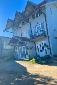 a large white house with a balcony and a driveway at Medalin Lake Gregory in Nuwara Eliya