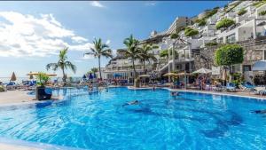 ein Pool in einem Resort mit Menschen, die darin schwimmen in der Unterkunft Bahia Holiday Club - Deluxe Private Suite - Puerto Rico in Mogán