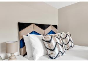 a white bed with a black and white pillow and a lamp at Stay & Explore: Convenient Studio - Prime Location in London