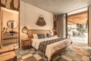 a bedroom with a large bed and a balcony at NAJ TULUM in Tulum