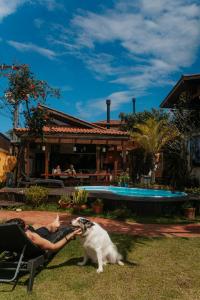 una mujer sentada en una silla jugando con un perro en Tucano House, en Florianópolis