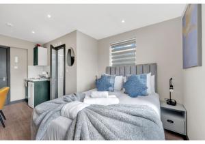 a bedroom with a large bed with blue pillows at A Place to Dream: Airy Studio in Serene Locale in London