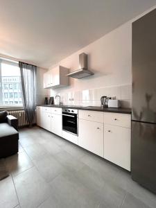 a kitchen with white cabinets and a black appliance at 93qm-4 Rooms-WiFi-City Centre in Kassel