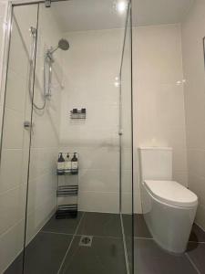 a bathroom with a toilet and a glass shower at Cosy Sunlit Home Away from Home in Baulkham Hills