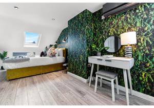 ein Schlafzimmer mit einer grünen Wand, einem Bett und einem Schreibtisch in der Unterkunft Earth Tones & Greenery: 4BR Flat Sleeps 8 in London