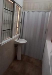 uma casa de banho com um lavatório branco e uma janela em Esquina La Argentina em San Luis